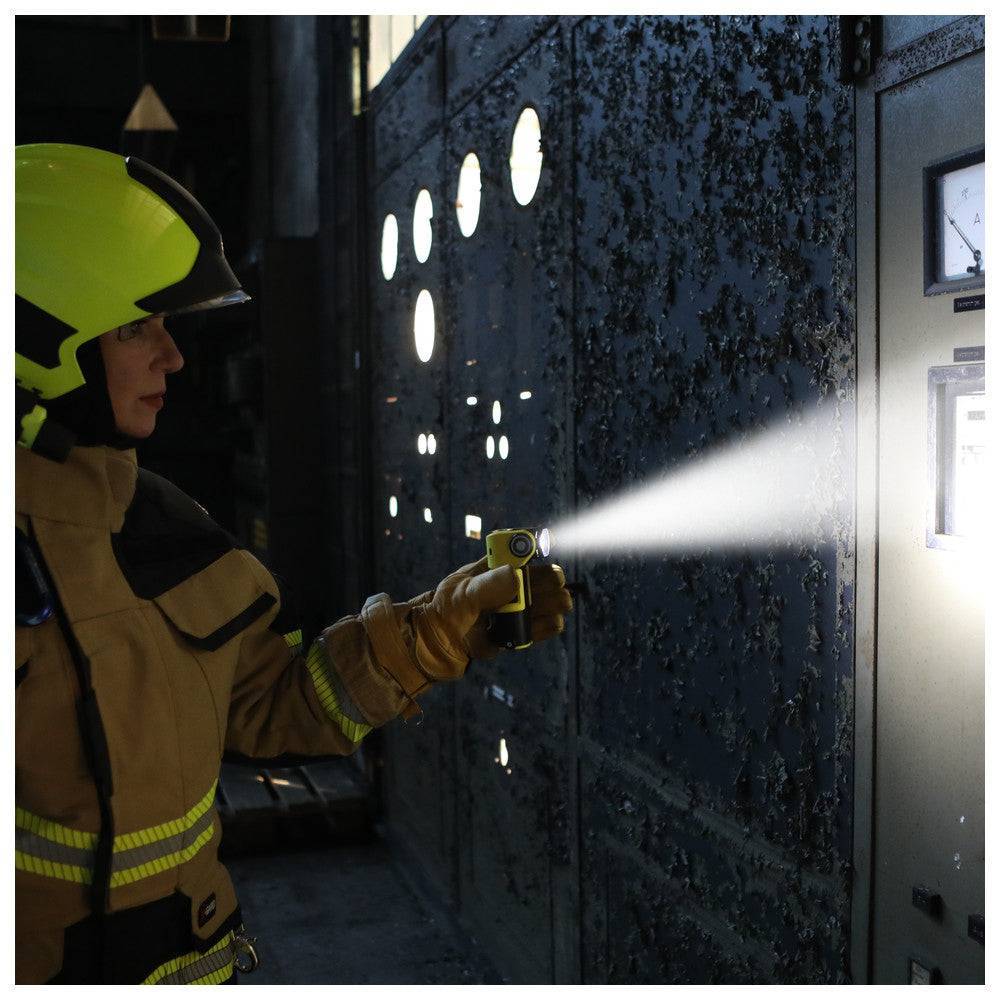 Feuerwehrmann nutzt Adalit L-3000 Handleuchte mit 300 lm LED zur Ausleuchtung eines dunklen Einsatzortes, ideal für Notfalleinsätze.