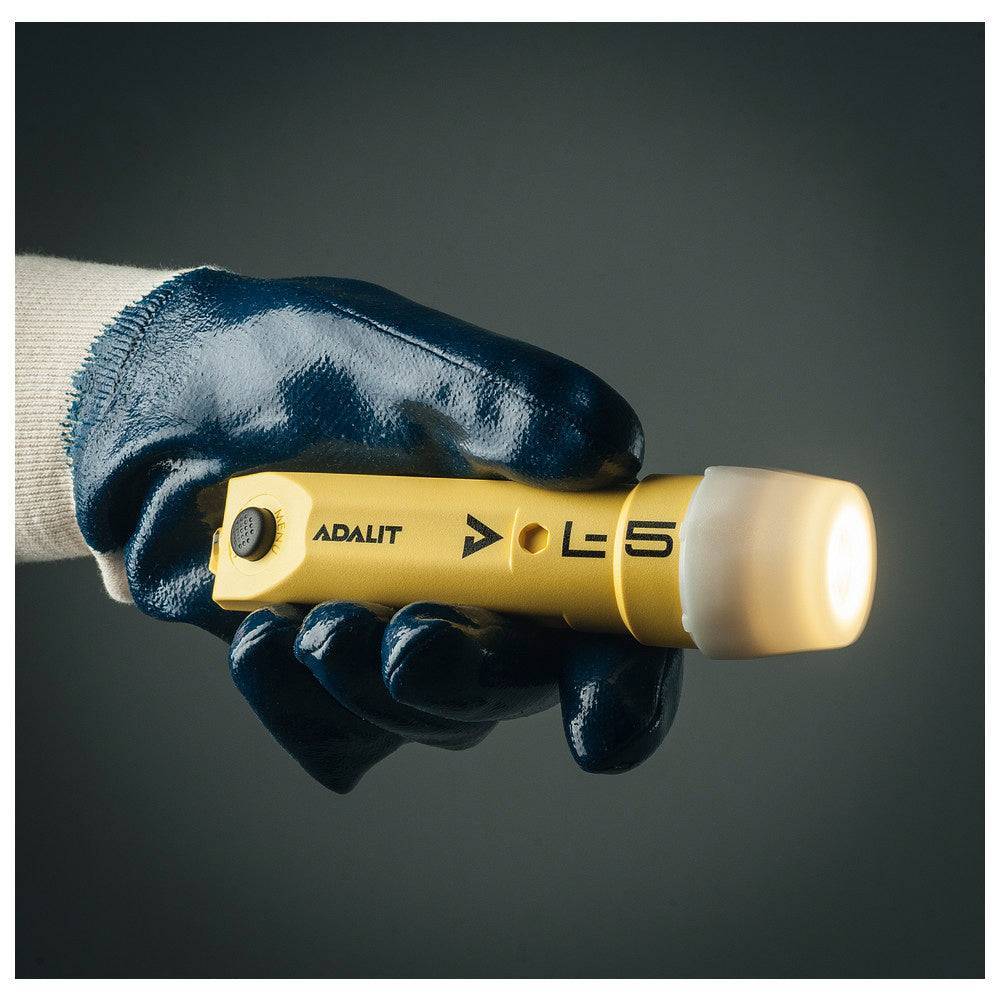 Adalit L-5 Plus Sensor-Helmlampe in gelber Ausführung, gehalten von einer Hand mit Schutzhandschuh – ideal für Feuerwehrhelme.