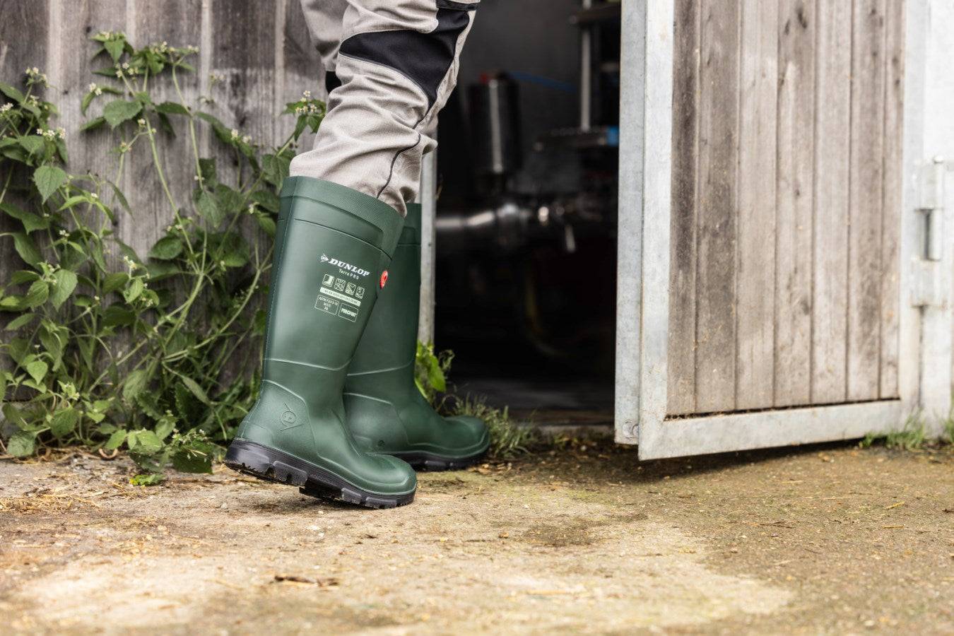Träger mit Dunlop® Purofort® TerraPRO S5 Sicherheitsstiefeln betritt Werkstatt. Gummistiefel S5 für kalte Arbeitsumgebungen bis -20 °C geeignet.