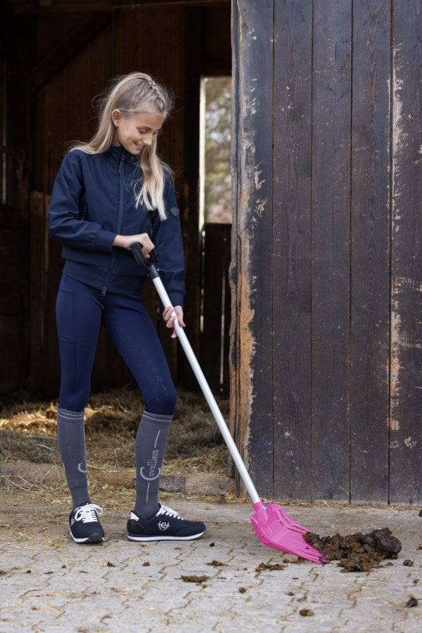 Mädchen benutzt die Dunggabel EcoFork Mini in Pink mit Stiel zum Ausmisten im Stall. Ideal für Kinder, leicht und ergonomisch geformt.