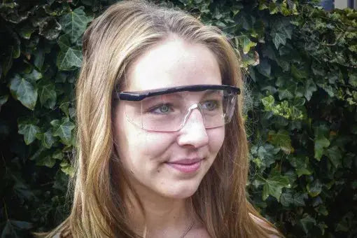 Frau trägt Schutzbrille mit verstellbarem Bügel transparent, ideal für Arbeiten im Innen- und Außenbereich.
