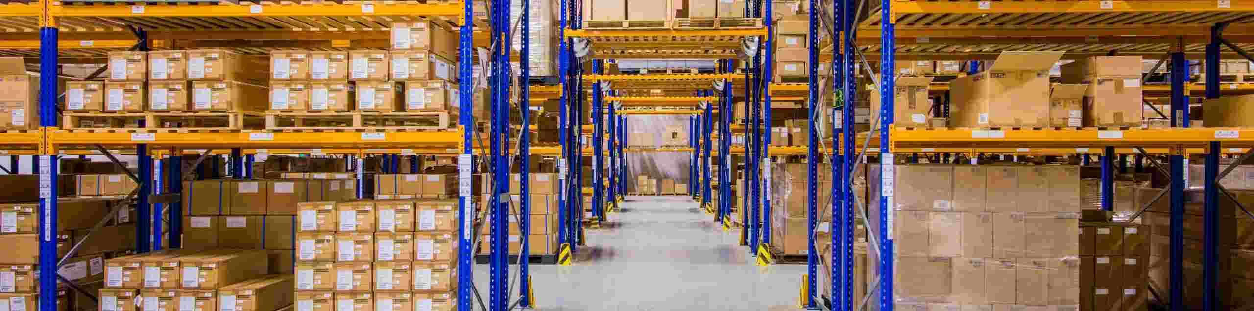 Lagerhalle mit hohen Regalen voller gestapelter Kartons und Kisten, organisiert für effiziente Lagerung und Logistik.