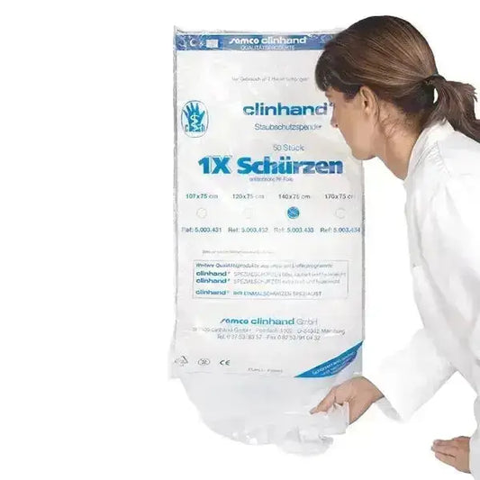 Frau in weißem Kittel entnimmt eine transparente Einweg-Schürze aus einem großen Spenderbeutel der Markeclinhand" mit Aufschrift "1X Schürzen, 50 Stück, Staubschutzspender".